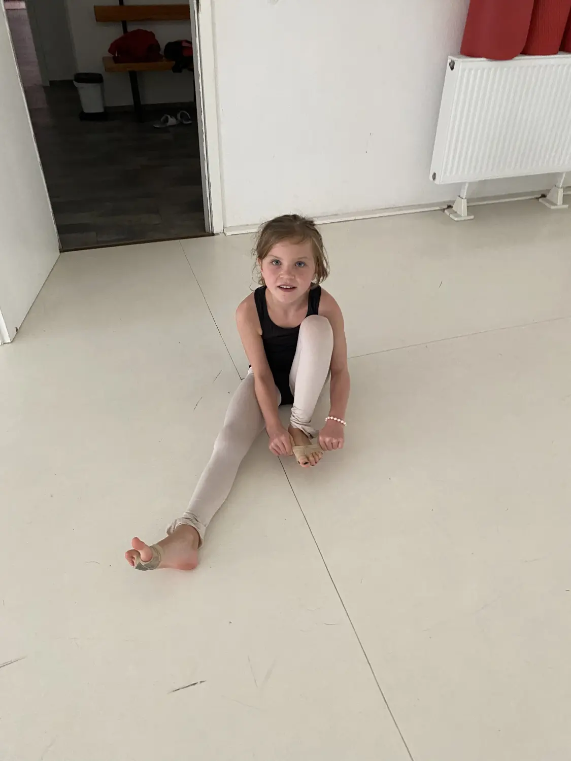 Tressa Arts & Entertainment School, ein Mädchen sitzt auf dem Boden und hält ihren Fuß